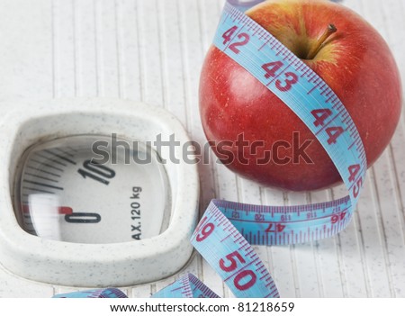 apple and measuring tape on the floor scales isolated on white