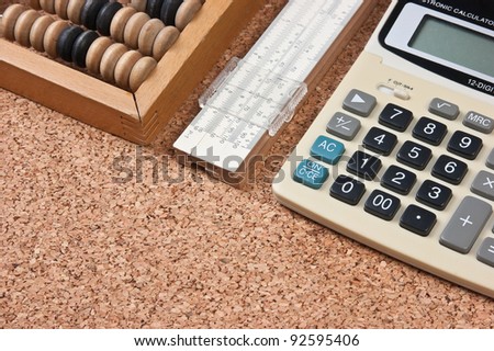 calculator, a wooden abacus and slide rule on a cork board