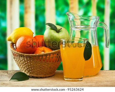 basket of fruit and juice on a wooden table in the garden
