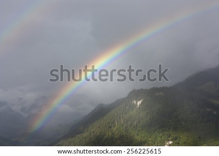 Double rainbow over foggy forested hills in Switzerland.