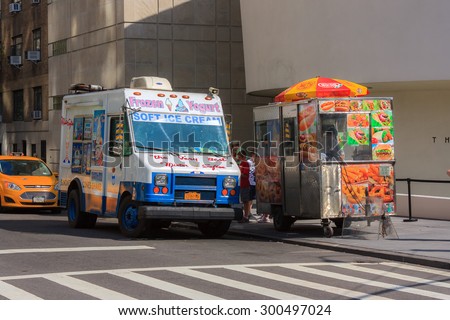 White and blue ice cream truck and hot dog cart on a street in New York City - July 10, 2015, 89th street, New York City, NY, USA