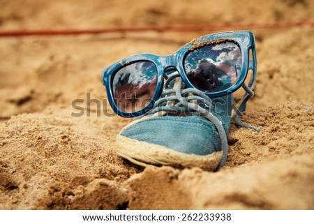 Creative funny old blue hipster shoe wearing sunglasses on the sand