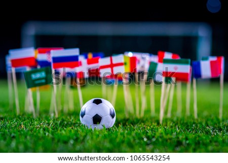 Football ball on green grass and all national flags of FIFA World Cup, Russia 2018.