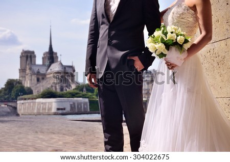 wedding couple with beautiful bouquet in front of the Notre Dame church in city of love, in Paris