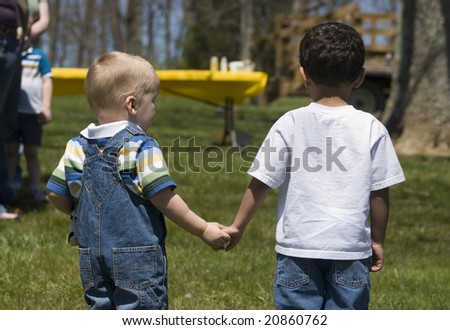 back view of two young boys holding hands at outdoor event
