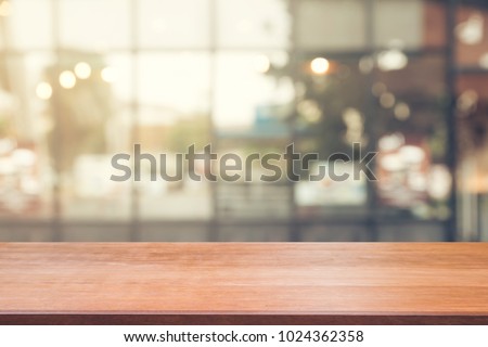 Wooden board empty table top on of blurred background. Perspective brown wood table over blur in coffee shop background -