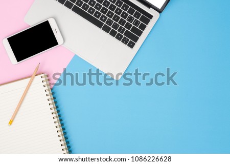 Office desk working space - Flat lay top view mockup photo of working space with laptop, mock up smartphone and blank notebook on pastel background. Blue pink color background working desk concept.