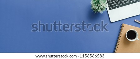 Minimal work space - Creative flat lay photo of workspace desk. Top view office desk with laptop, notebooks and coffee cup on blue color background. Panoramic banner background with copy space.