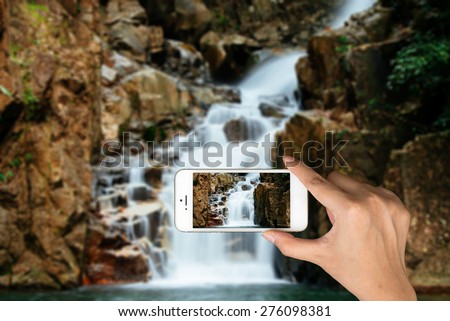 Smart phone camera taking photo picture of waterfall. Closeup of mobile phone camera screen photographing beautiful thailand landscape waterfall.