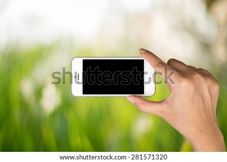 Woman hand hold and smart phone, tablet,cellphone on day light with green blurred nature background.