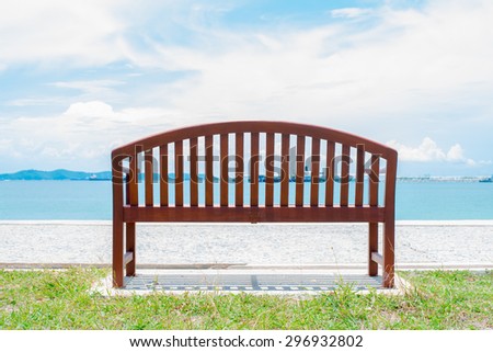 An empty wooden(wood) bench with a viewpoint looking out to sea. Cargo ship in the ocean in the sky. Summer season on the beach. Bulk-carrier ship in the sea. seascape.