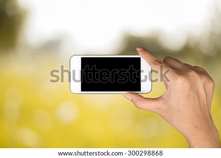 Woman hand hold and smart phone, tablet,cellphone on day light with yellow blurred nature background.