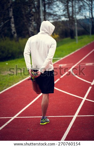 Single man in a sweatshirt stretching before run