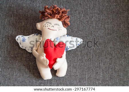 Happy Angel hugging red heart. Soft toy.