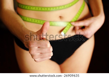 woman in black underwear with green tape measuring the waist