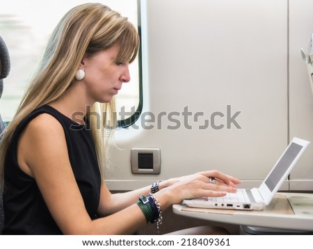 Young commuter woman using laptop computer on train