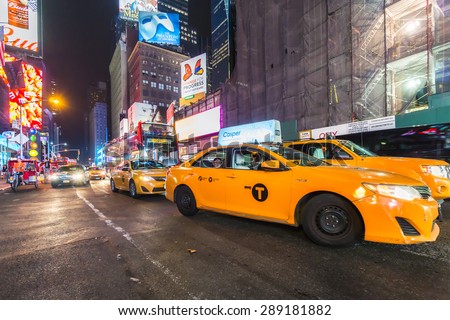 NEW YORK CITY - JUNE 12, 2015: Yellow taxi cabs and glowing electric signs near Times Square