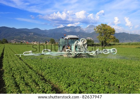 agriculture, tractor with chemical treatment spraying pesticide on cultivated field