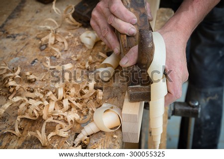Senior woodworker or carpenter doing woodworking on a plank of wood in workshop with manual plane