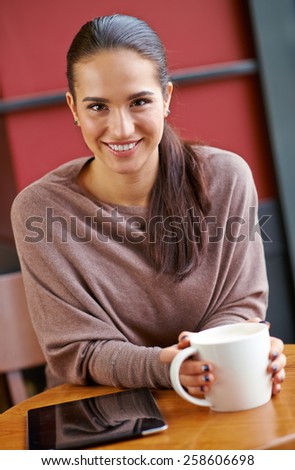 Happy brunette with mug in hands looking at camera