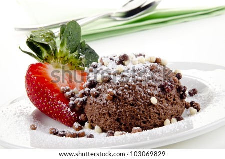 chocolate mousse with icing powder and strawberry on a plate