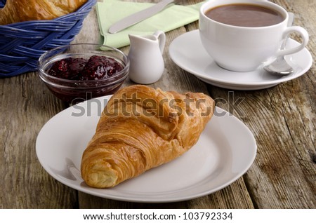 croissant, a French breakfast on a plate with a cup of coffee