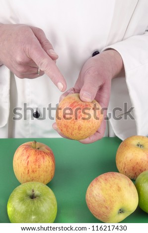 female chef in uniform shows with her index finger on a apple