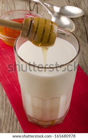 sweet honey is poured into a glass of warm milk