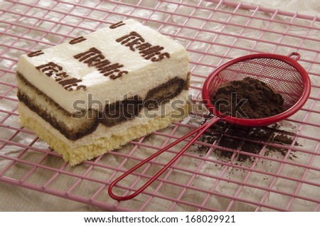 tiramisu and sieve with cocoa on a baking rack