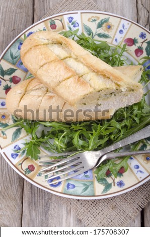 garlic bread with wild rocket salad on a plate
