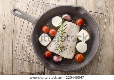 cod fillet with tomato, garlic, onion, rosemary and crushed pepper in a cast iron pan