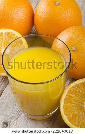 organic orange and freshly squeezed juice in a glass on rustic wood