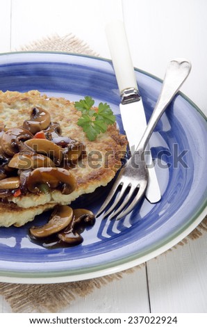 potato pancake with mushroom, onion, parsley and sauce on a blue plate