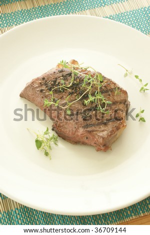 grilled pepper steak with organic herbs on a plate