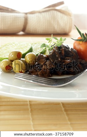 marinated cuttlefish with olive and tomato on a white plate