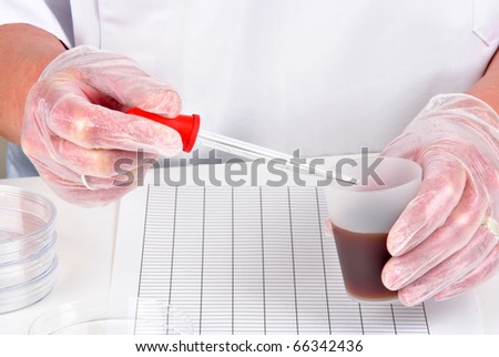 brown liquid and a pipette in the other hand