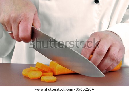 female chef cuts a carrot with a large kitchen knife