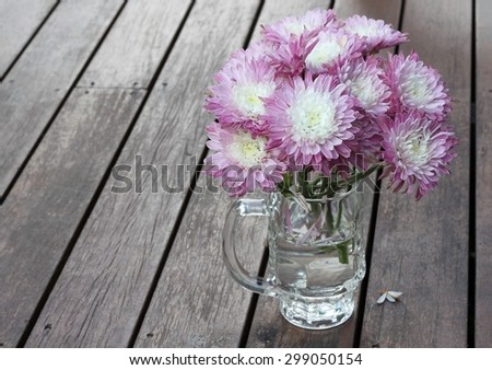 Rustic pink and white flowers in a beer glass with a timber floor background