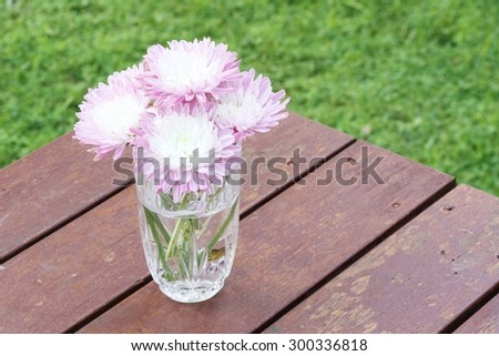 Rustic bunch of pink chrysanthemum flowers in a kitchen glass on a timber deck
