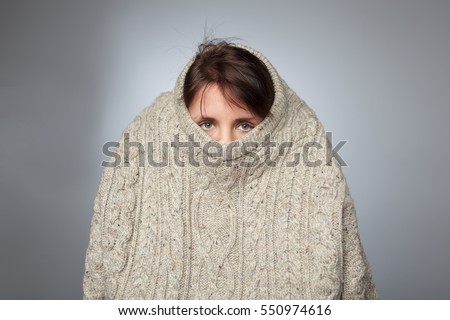 Girl pulls a large knitted sweater over her head. Despair and loneliness of depressed person