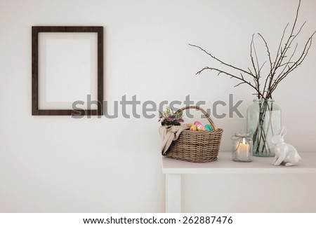 Easter abstract composition with easter basket, candle, frame and bunny in front of a white wall