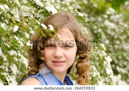 Girl with green eyes smiling on a background of white flowers