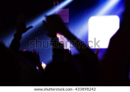 Blurred image of audience raising hands up in music festival.Crowd at concert. blurred movement. Motion blur