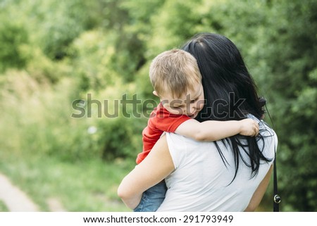 child and mom walk in the summer park. sad crying baby