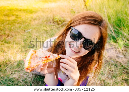 Woman outdoors in picnic eating pizza