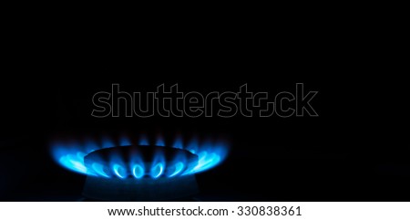burning gas stove hob blue flames close up in the dark on a black background