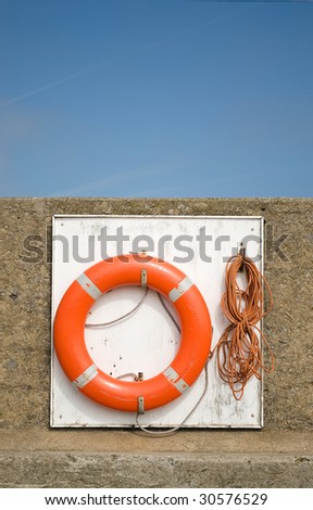 Orange life saving ring on edge of water