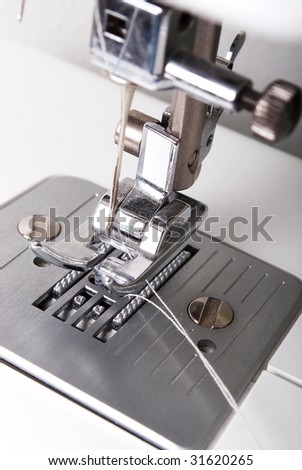 Sewing machine with silver foot and needle, white background