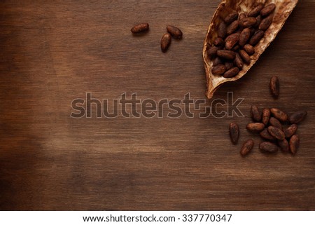 Roasted cocoa beans in the dry cocoa pod fruit on a dark wooden table
