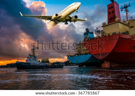 Merchant cargo ships assist by a tugboat are busy with mooring operations during sunset in port. Airplane is flying through the colorful clouds. Nice Industrial oil tanker/aviation background.